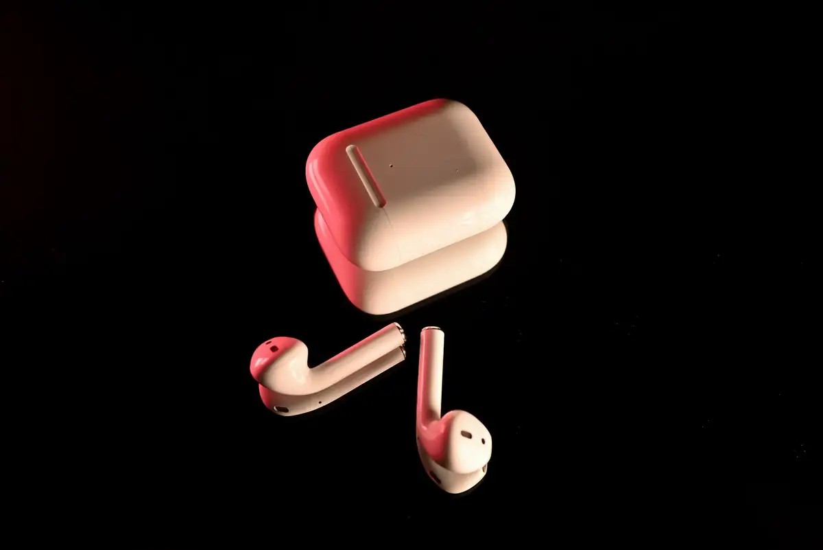 White wireless earbuds and their charging case on a dark background