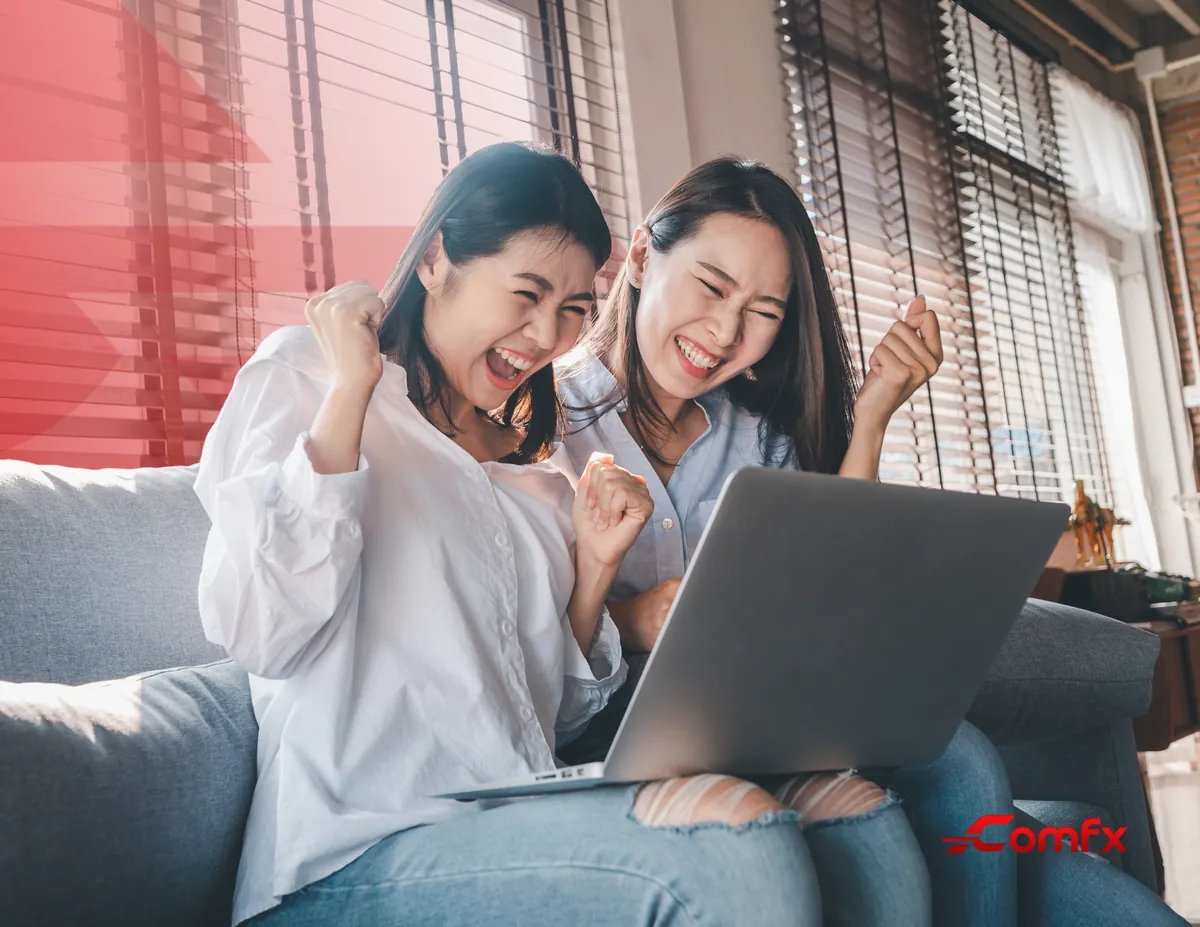 Two colleagues celebrating in front of a laptop on a sofa